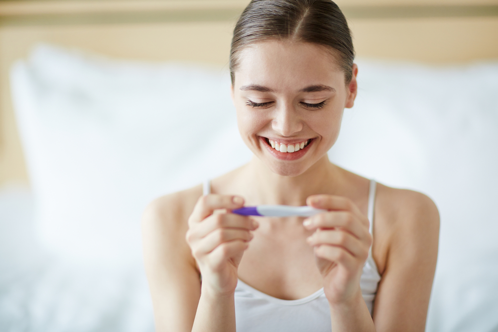 Young woman looking at pregnancy test in happiness