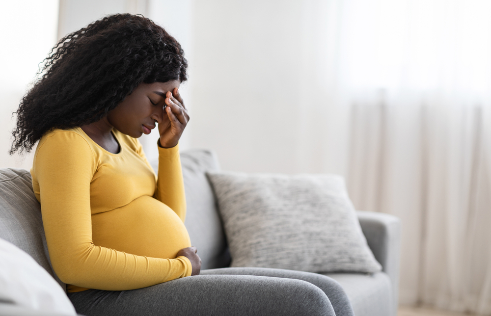 pregnant woman sitting on couch with eyes closed